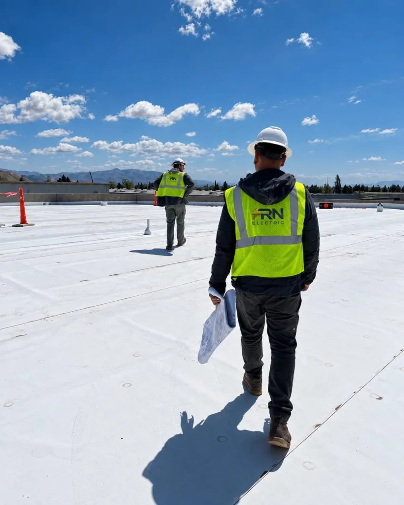 FRN Electric team members on a rooftop with project plans